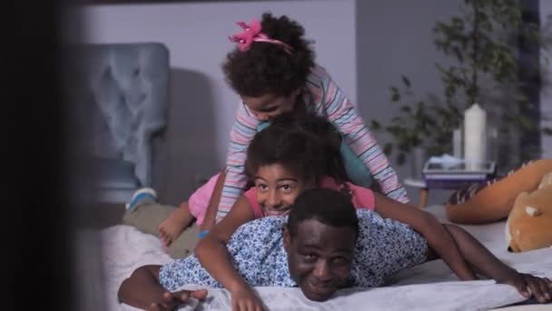Ευτυχισμένη μικτή οικογένεια που διασκεδάζει στο κρεβάτι στο σπίτι — Αρχείο Βίντεο