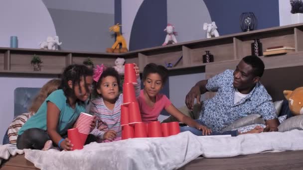 Familia de raza mixta jugando en la cama durante la cuarentena — Vídeos de Stock