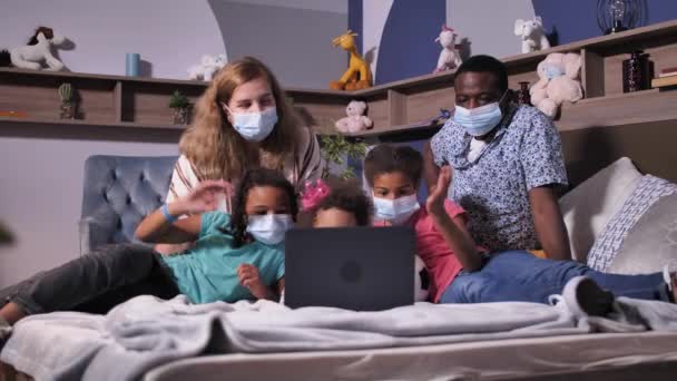 Família em máscaras durante o bate-papo por vídeo no laptop — Vídeo de Stock