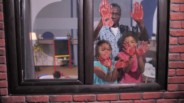 Familia negra haciendo huellas de manos rojas en la ventana — Vídeos de Stock