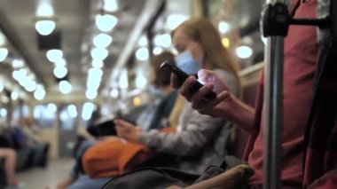 Akıllı telefon kullanan adam metro istasyonunda oturuyor.