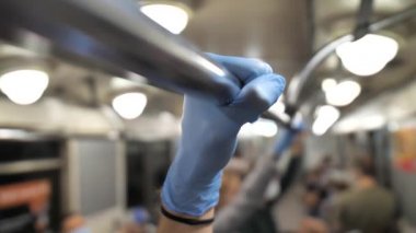 Metro korkuluklarında tıbbi eldiven giymiş bir erkek.