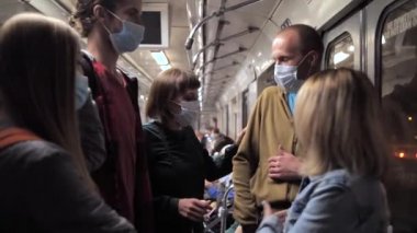 Yüzü maskeli bir grup insan metro vagonuna biniyor.