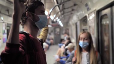 Metro treninde maske takan uzun boylu bir genç.