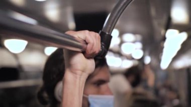 Metro treninde tırabzanı çıplak elle tutan adam.