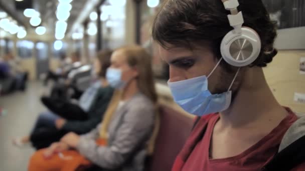 Man i ansiktet mask och hörlurar i tunnelbanetåg — Stockvideo