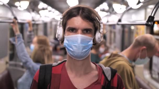 헤드폰을 끼고 지하철을 타고 있는 남자의 모습 — 비디오