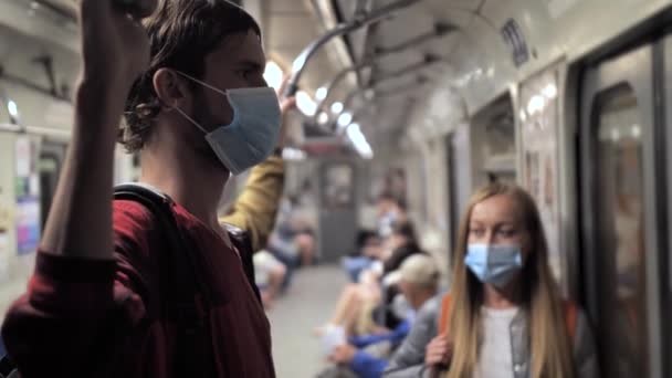 Lange jongeman draagt gezichtsmasker in metro trein — Stockvideo