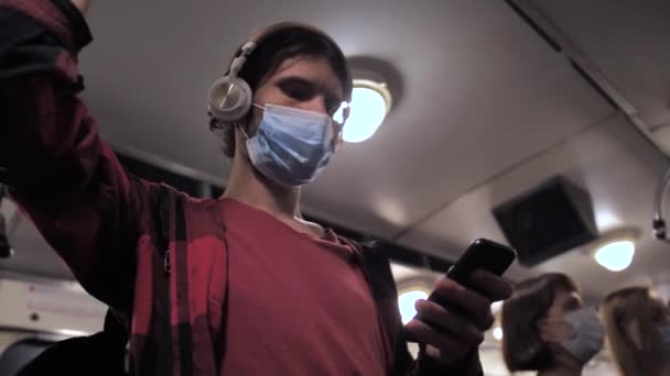 Gemaskerde man luistert naar muziek via de telefoon in de metro — Stockvideo
