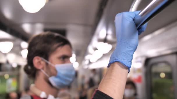 Человек в маске в перчатках держит перила в вагоне метро — стоковое видео