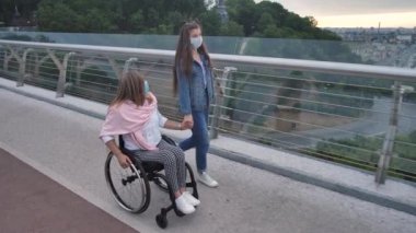 Dışarıda maskeli bir kızla dolaşan engelli bir anne.