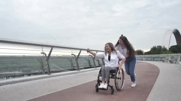 Счастливая девочка и мама катаются на инвалидной коляске — стоковое видео