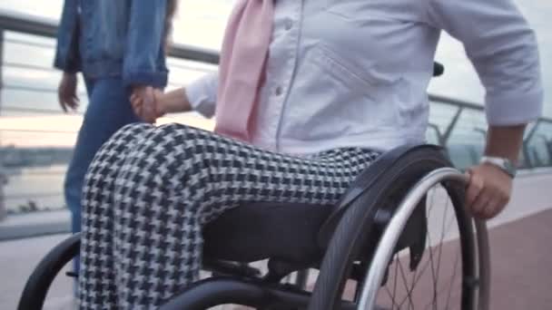 Tekerlekli sandalyedeki yetişkin kadın ve kızı yürüyüşe çıkmış. — Stok video