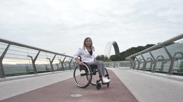 Pewna siebie kobieta jeżdżąca na wózku inwalidzkim wzdłuż kładki — Wideo stockowe