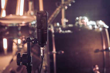 Bir kayıt stüdyo mikrofon ya da bir konser salonu kapatın ve arka planda bir akustik gitar ve davul kiti. Güzel renkli fenerler arka plan bulanık. Vintage tarzı müzik konsepti