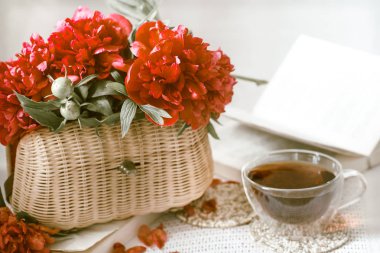 güzel taze çiçekler kırmızı peonies bir hasır çanta ve bir fincan çay beyaz koltuk üzerinde bir kitapla ile kompozisyon