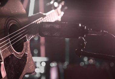 Stüdyo mikrofon bir akustik gitar yakın çekim, bir kayıt stüdyosu veya konser salonu, bir arka plan üzerinde odak modunda bir davul ile kaydeder. Güzel arka plan bulanık renkli fenerler