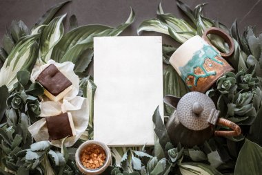 Bir çaydanlık ve yeşil yaprakları, yaratıcı bir arka plan bir arka plan üzerine bir kitap ile bir fincan