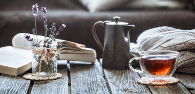 oturma odasında bir su ısıtıcısı ve ahşap bir masa, coziness kavramı üzerine bir kitap ile çay içme natürmort çay