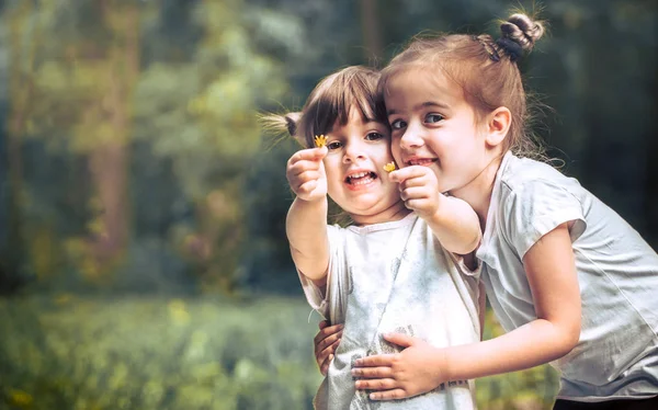 Zwei Kleine Schwestern Umarmen Einander Vor Einem Hintergrund Grüner Natur — Stockfoto