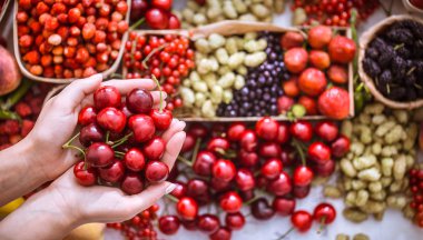 bir kız, bir arka plan farklı meyve, sağlıklı beslenme ve vitaminler kavramı karşı elinde taze kiraz
