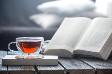 Natürmort bir fincan çay ile ahşap bir masa üzerinde açık bir kitap, coziness ve okuma kavramı