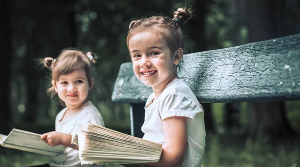 Zwei Kleine Schwestern Sitzen Auf Einer Parkbank Und Lesen Ein — Stockfoto