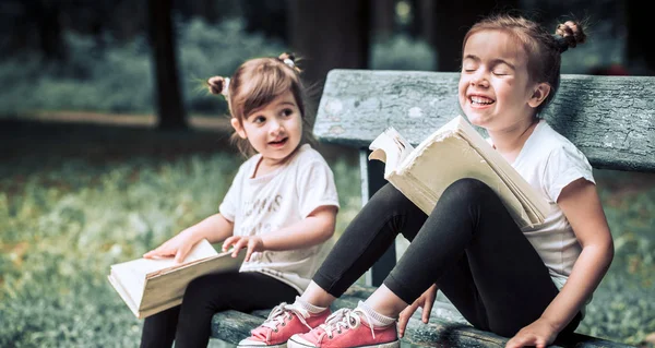 Zwei Kleine Schwestern Sitzen Auf Einer Parkbank Und Lesen Ein — Stockfoto