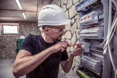 Erkek bir elektrikçi elektrik bağlantı kablosunu ile geçiş panosu çalışır, ekipman bağlar araçları, karmaşık iş kavramı, metin için yer