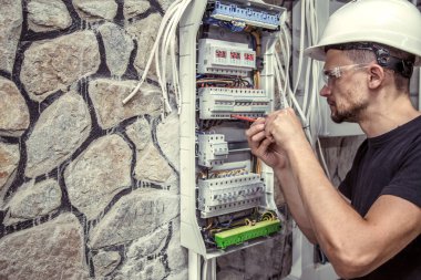Erkek bir elektrikçi elektrik bağlantı kablosunu ile geçiş panosu çalışır, ekipman bağlar araçları, karmaşık iş kavramı, metin için yer