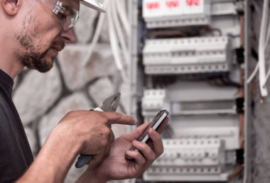 Erkek bir elektrikçi elektrik bağlantı kablosunu ile geçiş panosu çalışır, ekipman bağlar araçları, karmaşık iş kavramı, metin için yer