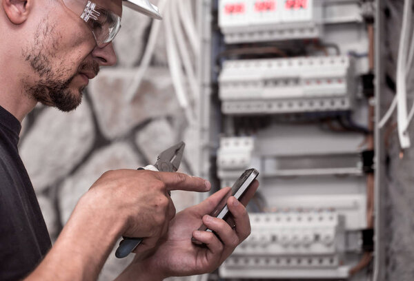 мужчина-электрик работает в коммутаторе с электрическим соединительным кабелем, соединяет оборудование с инструментами, концепцию сложной работы, пространство для текста
