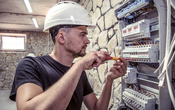 Erkek bir elektrikçi elektrik bağlantı kablosunu ile geçiş panosu çalışır, ekipman bağlar araçları, karmaşık iş kavramı, metin için yer