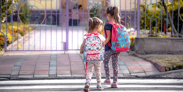 Çocukların okula, mutlu öğrenciler okul sırt çantaları ile gitmek ve birlikte, el ele tutuşarak, eğitimle kızlar, metin için yer kavramını karşıdan karşıya