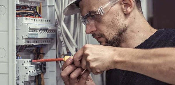 Erkek bir elektrikçi elektrik bağlantı kablosunu ile geçiş panosu çalışır, ekipman bağlar araçları, karmaşık iş kavramı, metin için yer