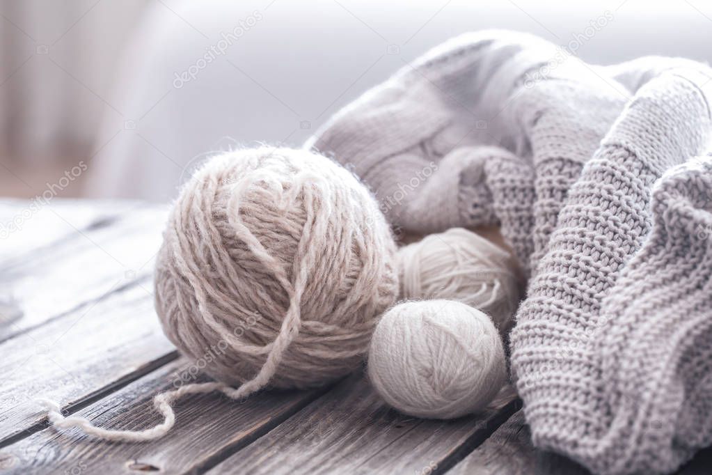 home hobbies, cozy knitted sweaters with a ball of yarn in the living room on a wooden background