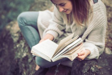 Genç kız sıcak kazaklı doğa görünümü yukarıdan, eğlence ve hobi kavramı üzerine bir kitap okur