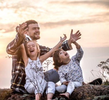 Mutlu sevgi dolu aile, baba ile iki günbatımı üzerinde yüksek bir güzel dağ oturmuş, Aile ilişkileri ve dostluk kavramı, küçük şirin kızları oynuyor