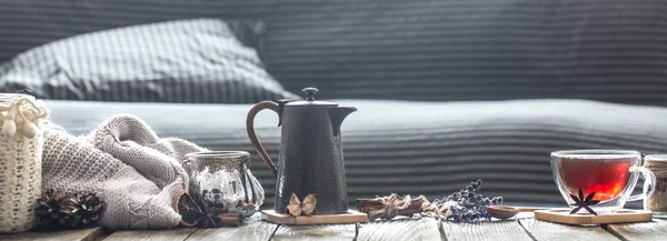 still life cozy living room with elements of home decor and a cup of tea with a teapot on a wooden table