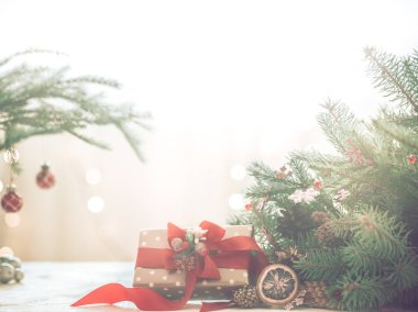 Noel coziness ışıkları ve bir Noel ağacı ve tablo, metin için yer kırmızı fiyonklu bir hediye dalları ile hafif bir arka plan üzerinde bir odada