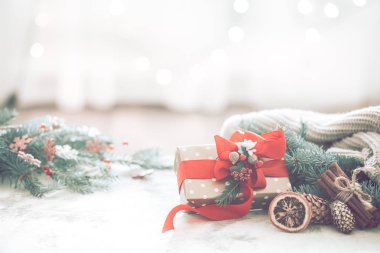 Noel coziness ışıkları ve bir Noel ağacı ve tablo, metin için yer kırmızı fiyonklu bir hediye dalları ile hafif bir arka plan üzerinde bir odada