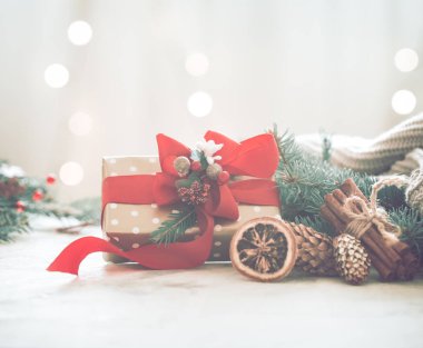 Noel coziness ışıkları ve bir Noel ağacı ve tablo, metin için yer kırmızı fiyonklu bir hediye dalları ile hafif bir arka plan üzerinde bir odada