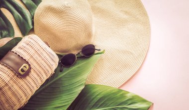 Büyük plaj şapka ve çanta, tropikal yaprakları ile pembe bir arka plan üzerinde şık natürmort