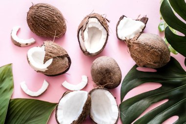 Taze Hindistan cevizi yarısı ve tropikal yaprak pop art, pembe bir arka plan. Üstten görünüm, yakın çekim, yaratıcı kavramı