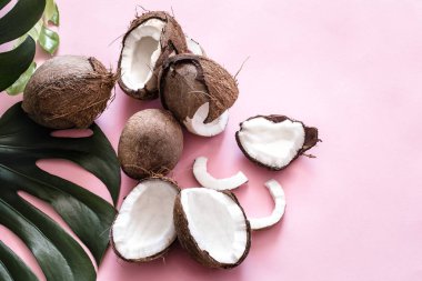 Taze Hindistan cevizi yarısı ve tropikal yaprak pop art, pembe bir arka plan. Üstten görünüm, yakın çekim, yaratıcı kavramı