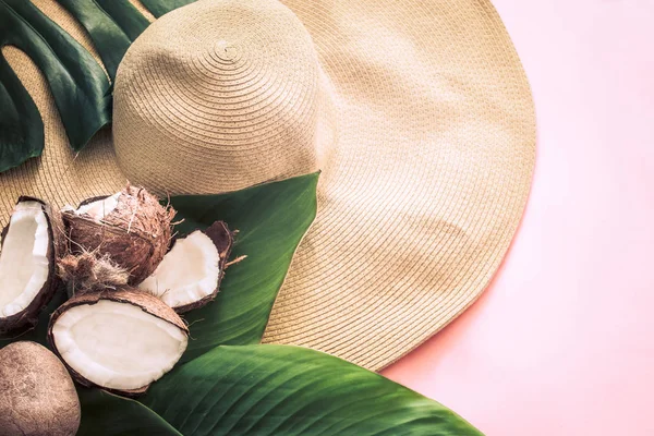 Summer stylish still life with beach hat and coconut on a pink background, pop art. Top view, close-up, creative concept