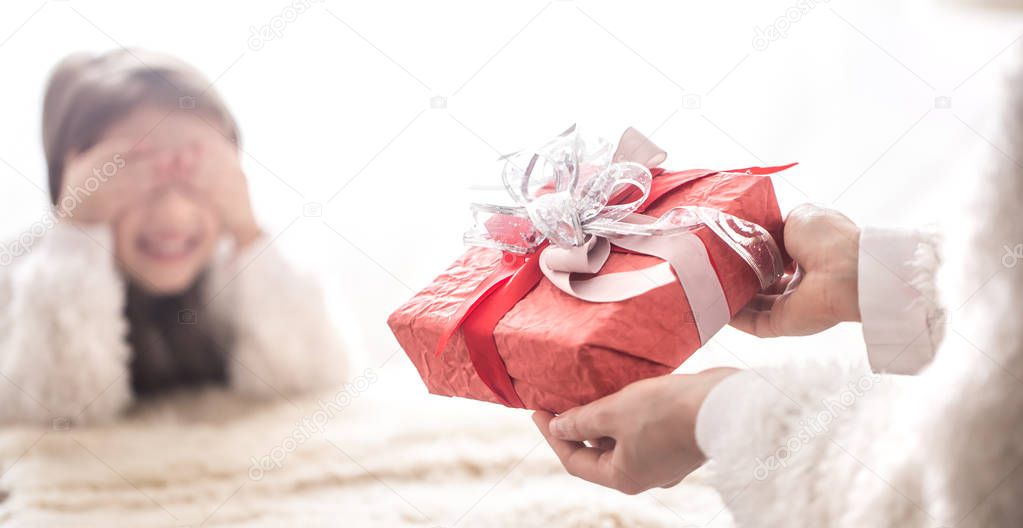 Christmas and new year concept, Mom gives a gift to a little cute daughter, a place for text on a light background