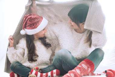 Noel ve yeni yıl kavramı, anne ve sevimli kızı oturma odasında kanepede yürütme