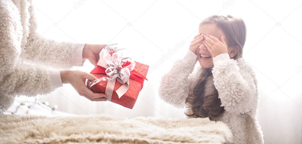 Christmas and new year concept, Mom gives a gift to a little cute daughter, a place for text on a light background