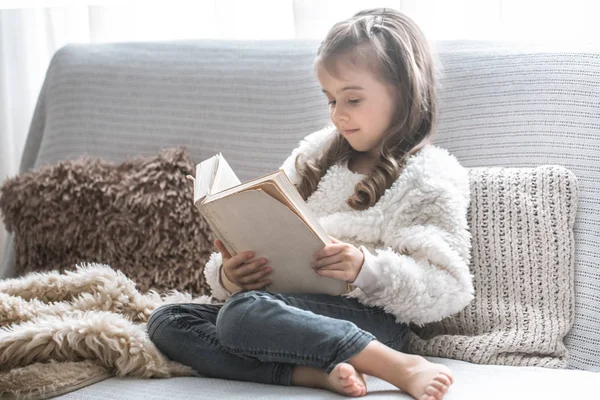 Маленькая Девочка Читает Книгу Удобном Диване Уютной Гостиной Себя Дома — стоковое фото